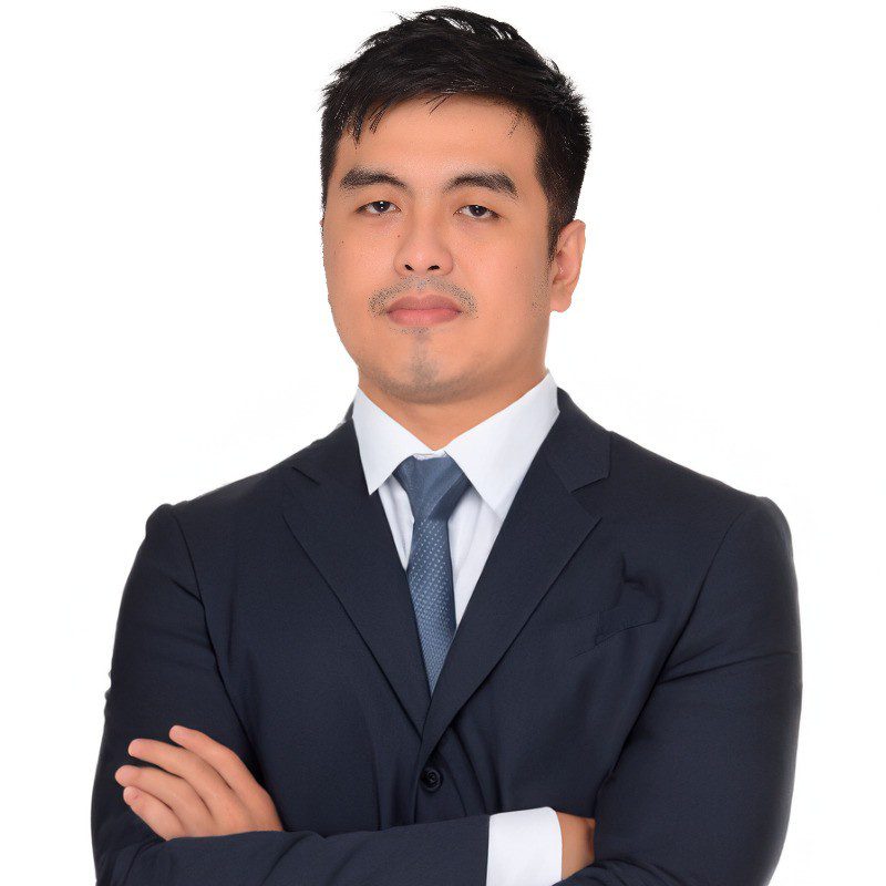 Danny, founder of Intensified Achiv Solar, photographed against a clean white backdrop — arms crossed, navy suit, direct gaze.
